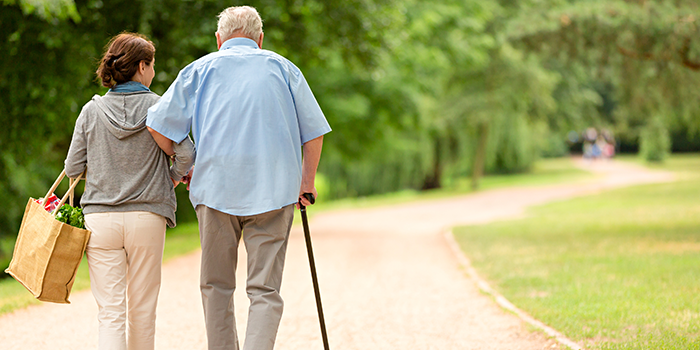 Health aide assisting senior walking outside