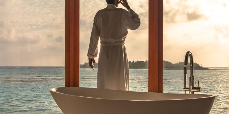 Man in luxury bathroom overlooking coastal views